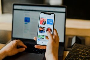 Man working with laptop and phone showing mental overload, distraction, and divided attention at desk
