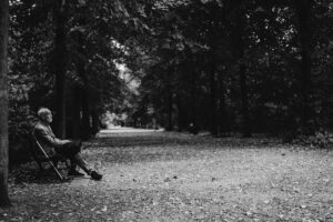 elderly man sitting peacefully in a park reflecting on presence and social media loneliness