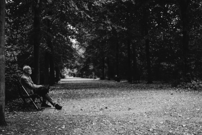 elderly man sitting peacefully in a park reflecting on presence and social media loneliness