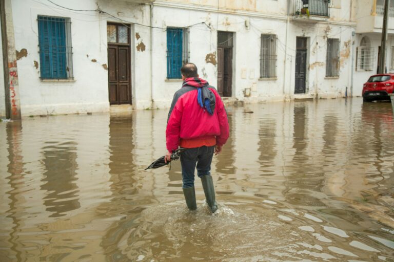 Man walking through waterlogged street during urban flooding caused by heavy rainfall