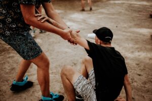 A man helping another person stand up, symbolizing compassion, responsibility, and the importance of good character.