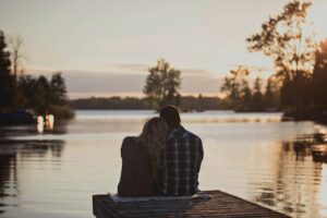 Young couple sharing a quiet moment together by a lake at sunset