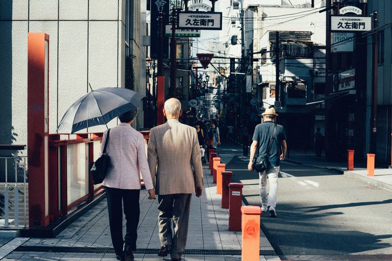 Older Japanese couple walking together on a street in Osaka